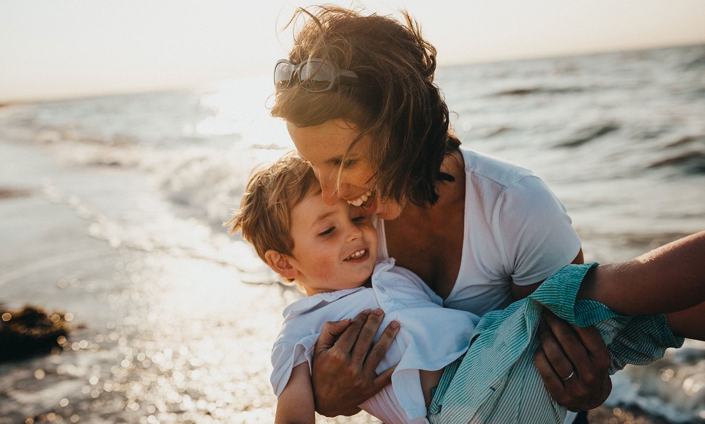 A mother lifting her son at the beach